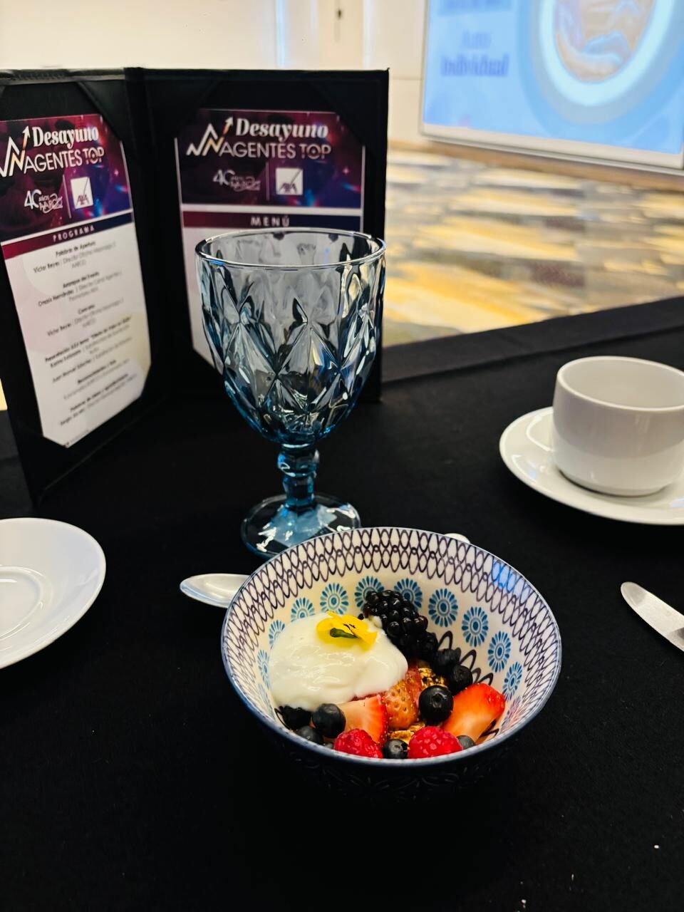 Desayuno formal para evento corporativo con bowl de fruta, yogurt y montaje de mesa con menú impreso