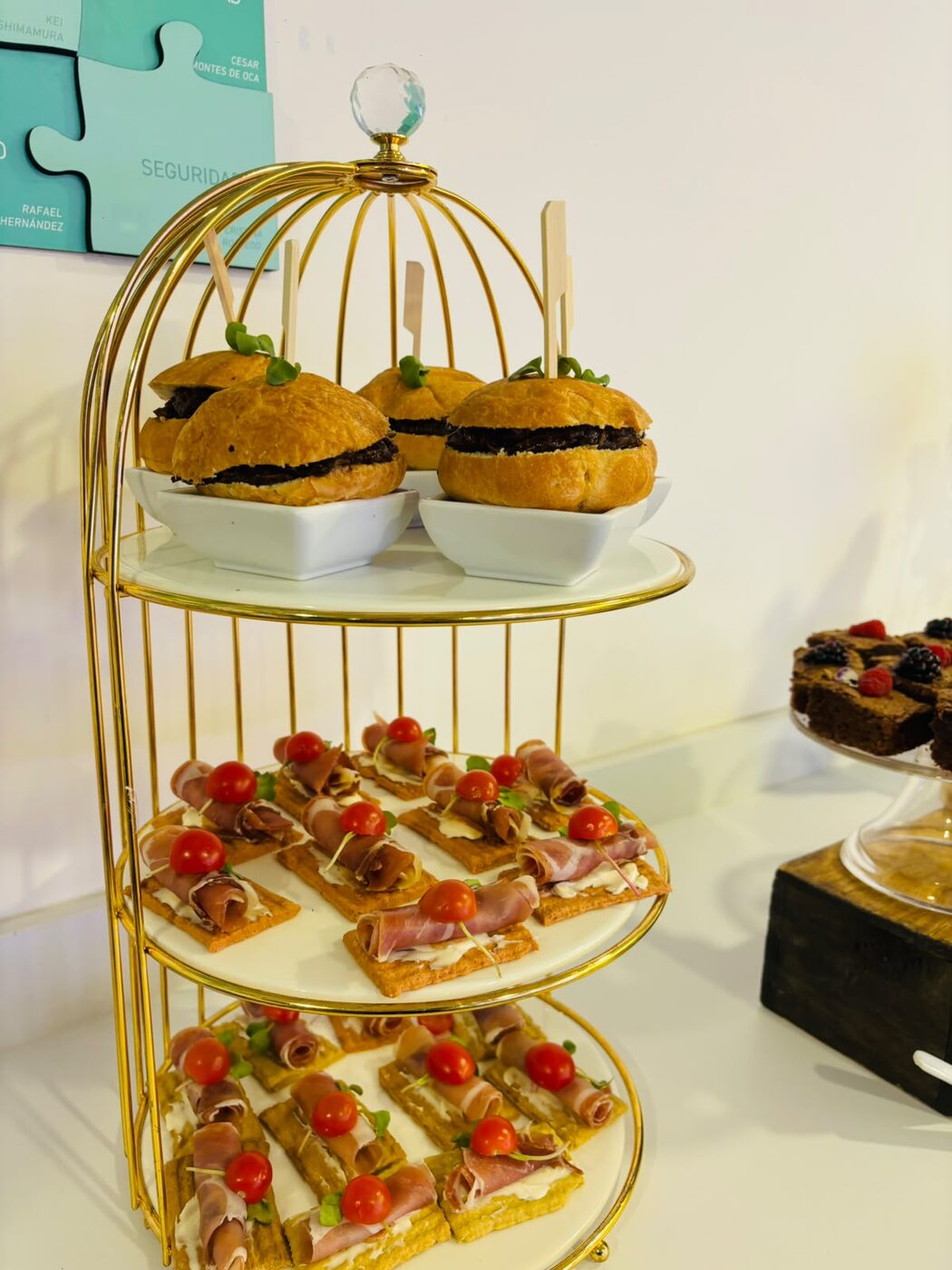 Torre de bocadillos dorada con mini panes rellenos y canapés de jamón serrano en coffee break empresarial