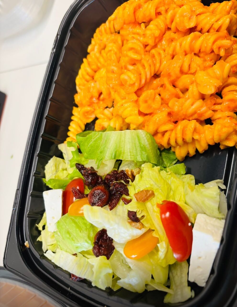 Box lunch con pasta y ensalada fresca en contenedor individual
